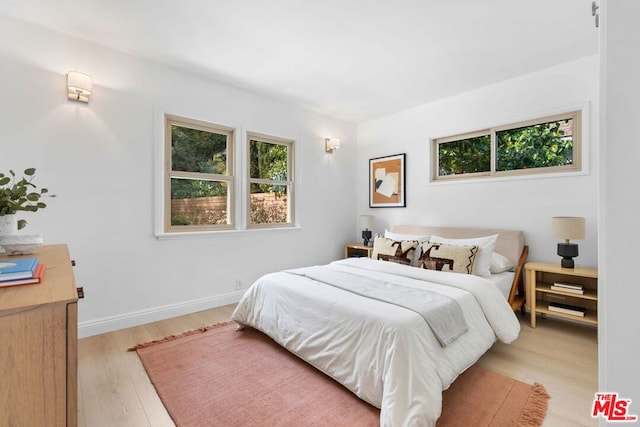 bedroom with multiple windows and light wood-type flooring