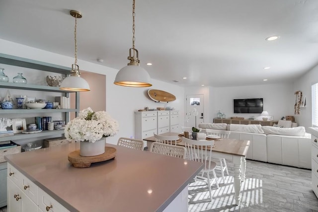 kitchen featuring a breakfast bar area, hanging light fixtures, a center island, light hardwood / wood-style floors, and white cabinets