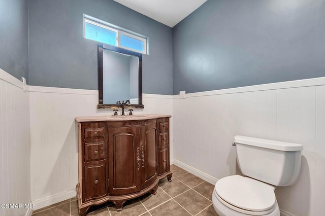 bathroom with tile patterned flooring, vanity, wood walls, and toilet