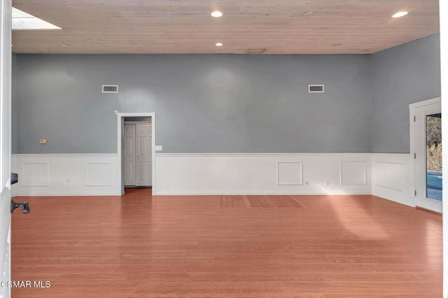 empty room with wooden ceiling, light wood-type flooring, and a skylight