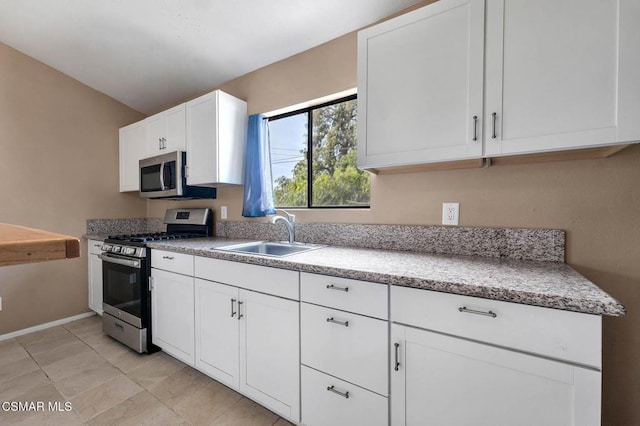 kitchen with stainless steel appliances, sink, light tile patterned floors, and white cabinets