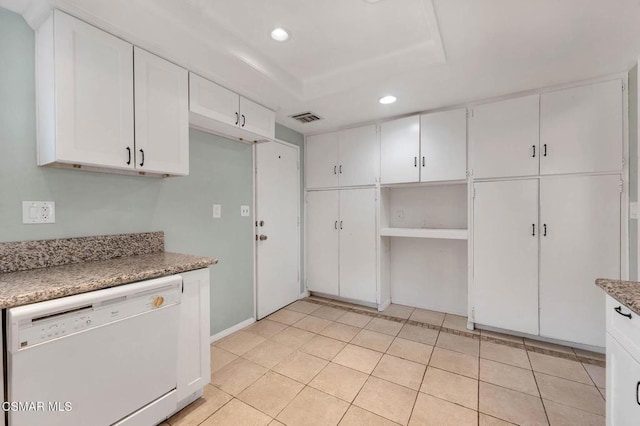 kitchen with stone countertops, dishwasher, white cabinets, light tile patterned floors, and a tray ceiling