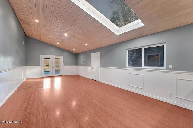 spare room featuring vaulted ceiling with skylight, wooden ceiling, light wood-type flooring, and french doors