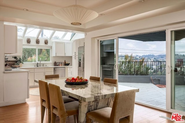 dining area featuring sink, a wealth of natural light, light wood-type flooring, and a skylight