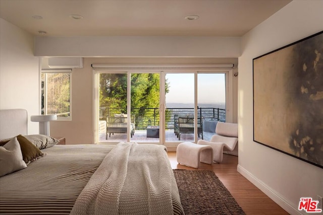 bedroom featuring access to outside, a wall unit AC, and wood-type flooring