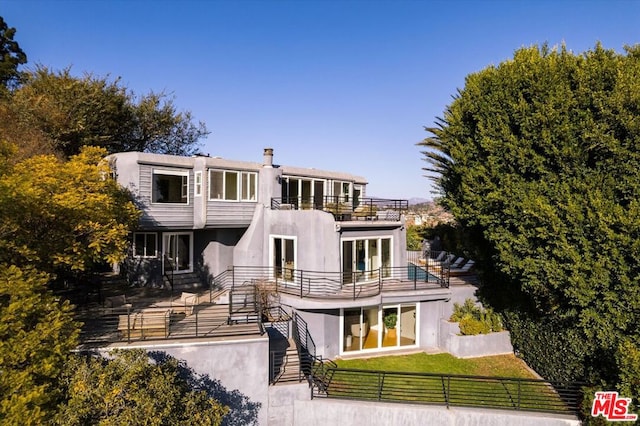 rear view of house with a balcony and a yard