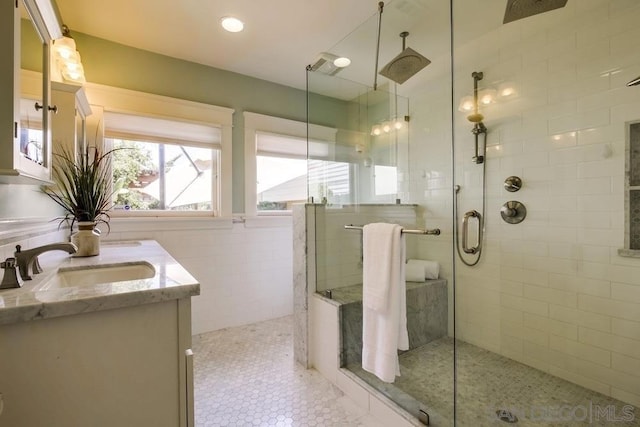 bathroom featuring vanity, a shower with shower door, and tile walls