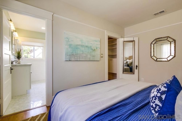 bedroom featuring hardwood / wood-style flooring, a walk in closet, and a closet