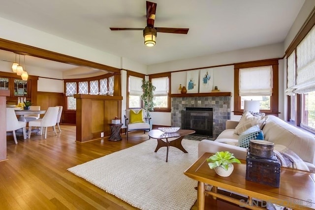 living room featuring hardwood / wood-style flooring, a wealth of natural light, a tile fireplace, and ceiling fan