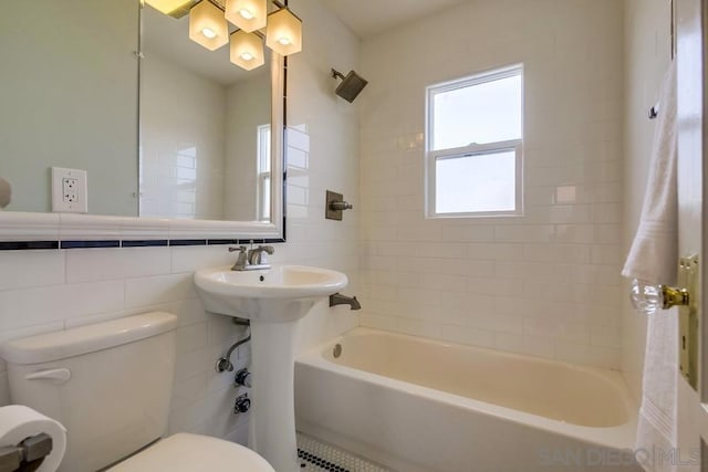 bathroom with tiled shower / bath, toilet, and tile walls