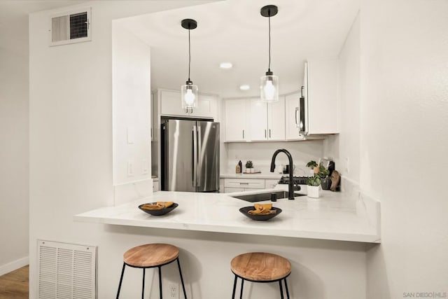 kitchen with a breakfast bar, sink, white cabinets, kitchen peninsula, and stainless steel appliances