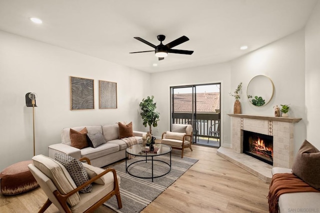 living room featuring ceiling fan, a fireplace, and light hardwood / wood-style flooring