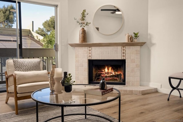 sitting room featuring a tiled fireplace and wood-type flooring