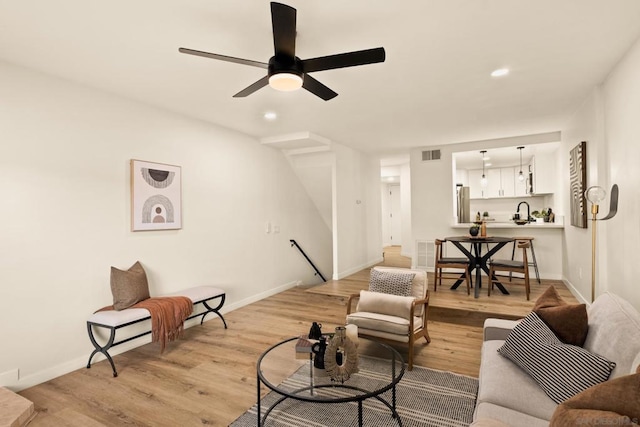 living room with ceiling fan and light hardwood / wood-style flooring