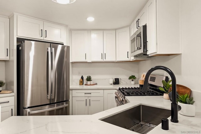 kitchen featuring light stone counters, appliances with stainless steel finishes, and white cabinets