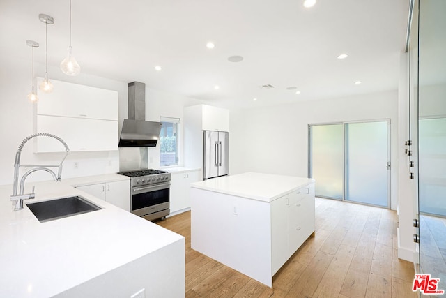 kitchen featuring a kitchen island, decorative light fixtures, sink, high end stainless steel range, and wall chimney range hood