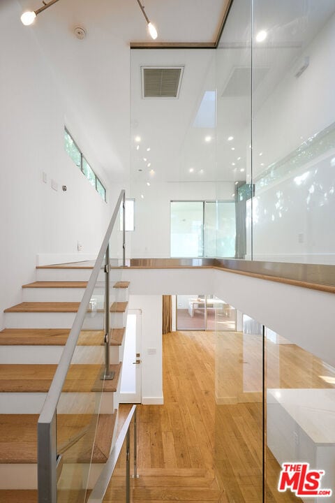 staircase featuring hardwood / wood-style flooring and a high ceiling