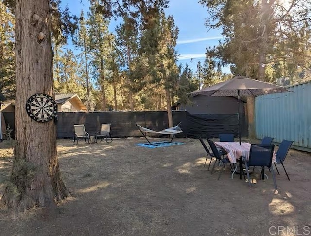 view of yard featuring a patio area, outdoor dining area, and fence