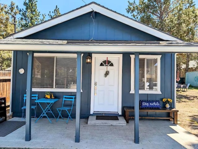 property entrance with board and batten siding and fence