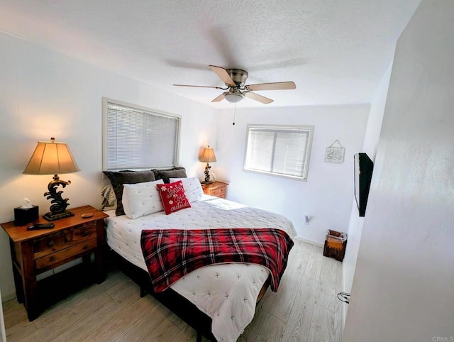 bedroom featuring light wood-type flooring, baseboards, a textured ceiling, and a ceiling fan