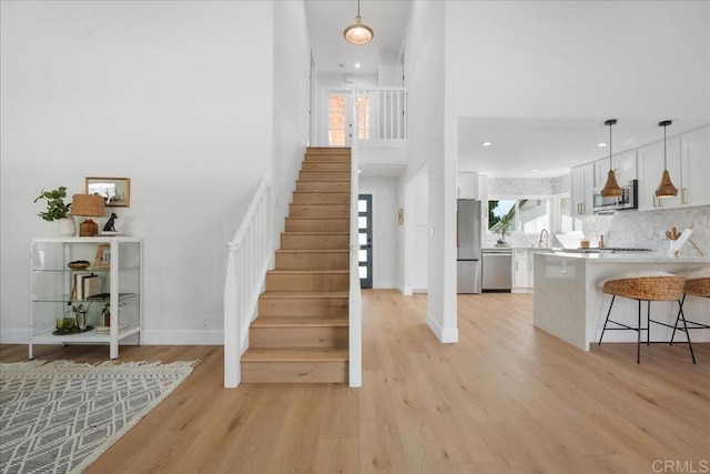 interior space with a towering ceiling, sink, and light hardwood / wood-style floors