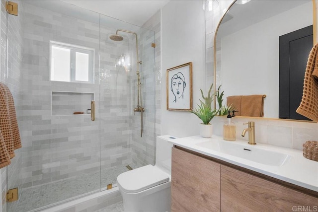 bathroom with vanity, a shower with shower door, decorative backsplash, and toilet