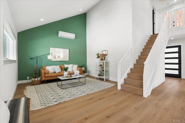 living room featuring a wall mounted air conditioner, light hardwood / wood-style flooring, and high vaulted ceiling