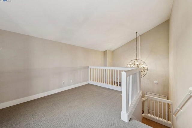 carpeted empty room with a notable chandelier and vaulted ceiling