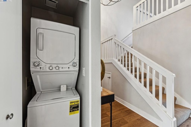 clothes washing area with stacked washer / dryer and hardwood / wood-style flooring