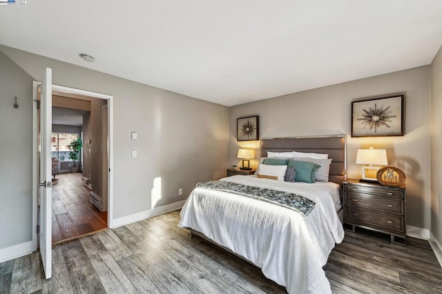 bedroom featuring dark hardwood / wood-style flooring and a baseboard heating unit