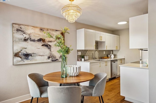 dining area featuring sink, an inviting chandelier, and light hardwood / wood-style flooring