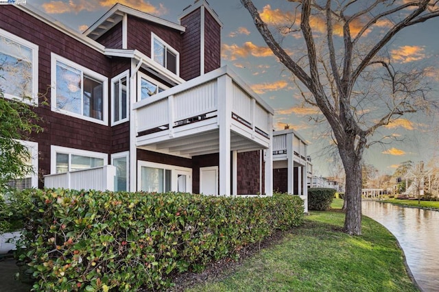 property exterior at dusk featuring a yard