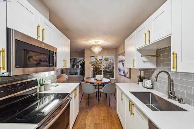 kitchen featuring sink, light hardwood / wood-style flooring, white cabinets, stainless steel appliances, and backsplash