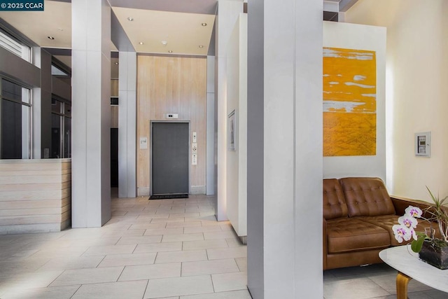 hall featuring a towering ceiling, elevator, and light tile patterned floors