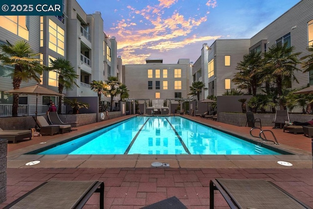 pool at dusk with a patio area