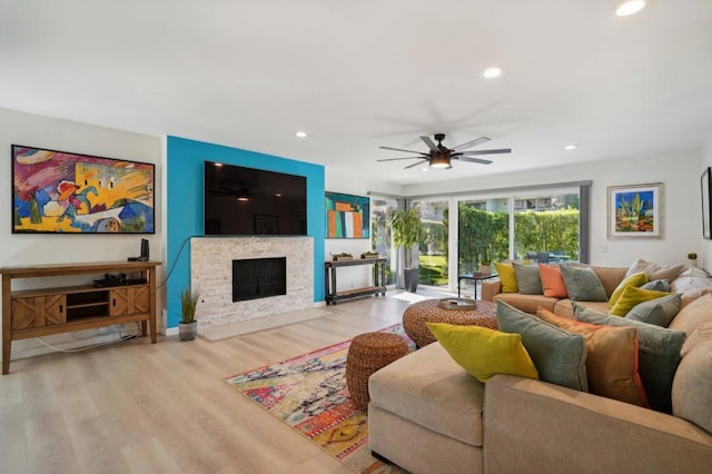 living room featuring ceiling fan, a fireplace, and light hardwood / wood-style floors