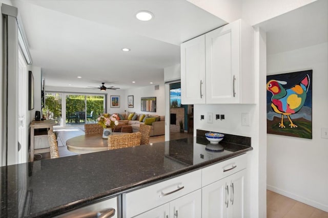 kitchen featuring ceiling fan, light hardwood / wood-style flooring, dark stone counters, and white cabinets