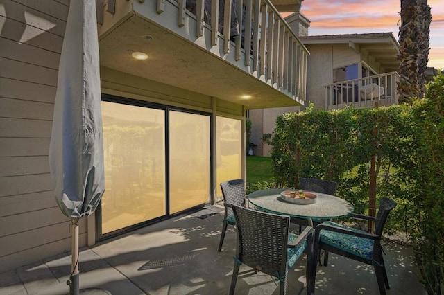 patio terrace at dusk featuring a balcony