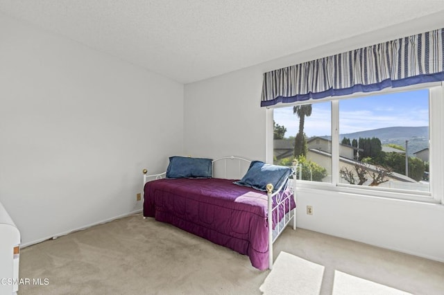 carpeted bedroom featuring a mountain view and a textured ceiling