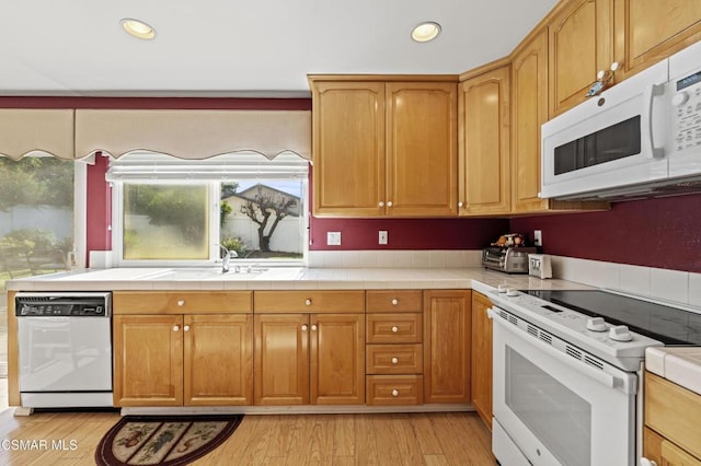 kitchen with light hardwood / wood-style flooring, sink, white appliances, and tile counters