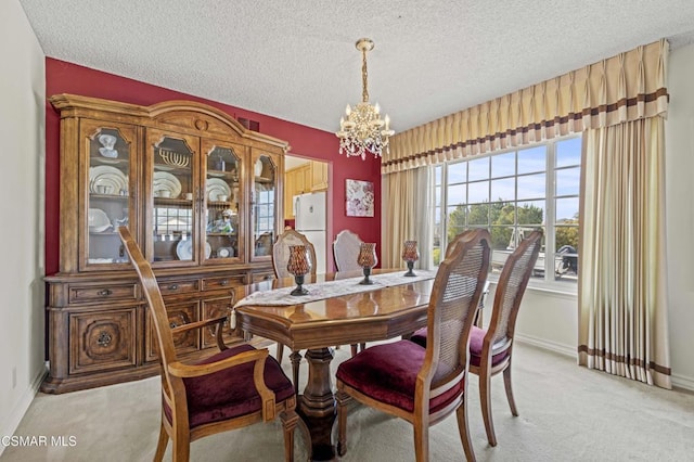 carpeted dining room featuring a notable chandelier and a textured ceiling