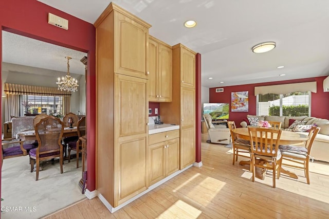 kitchen with pendant lighting, light brown cabinets, a notable chandelier, and light wood-type flooring