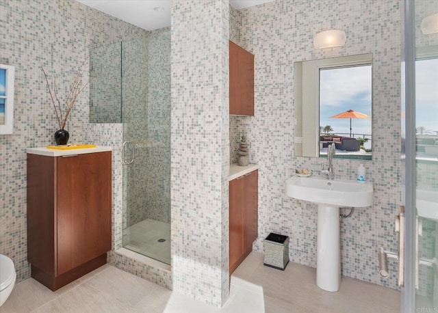 bathroom featuring a shower with door, sink, tile walls, and tile patterned floors