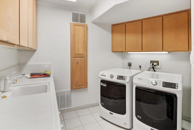 clothes washing area with cabinets, washing machine and dryer, sink, and light tile patterned flooring