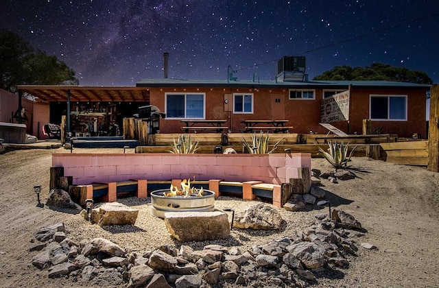 rear view of house with central AC unit and a fire pit