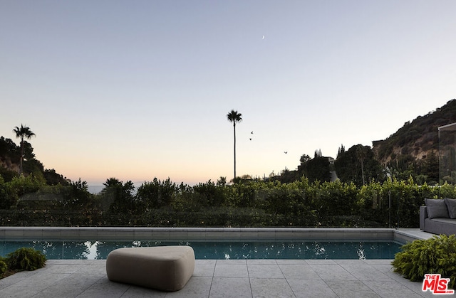 pool at dusk featuring a patio