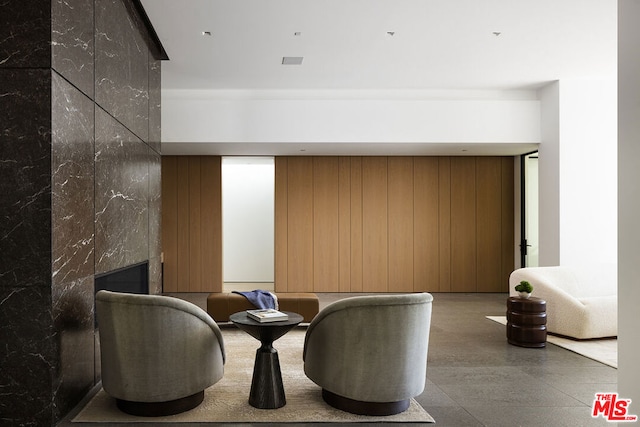 sitting room featuring wooden walls and a premium fireplace