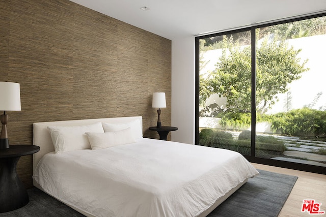 bedroom featuring floor to ceiling windows, wood-type flooring, and access to outside