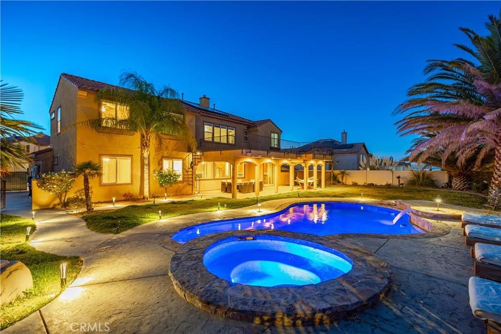 pool at dusk with an in ground hot tub and a patio area