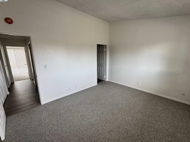 empty room featuring a textured ceiling and dark colored carpet